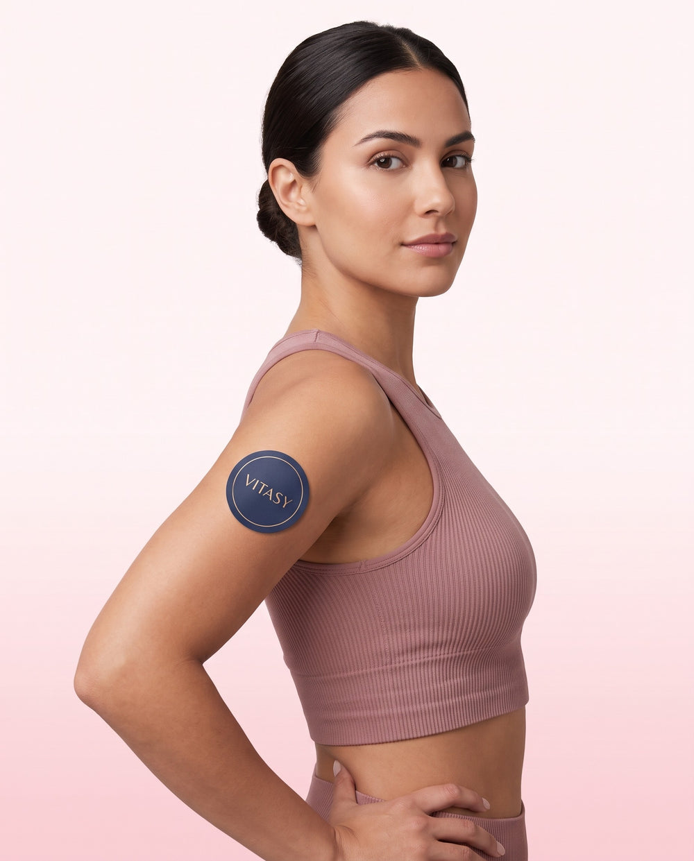 Woman in a pink rib top with a Vitasy patch on her upper arm
