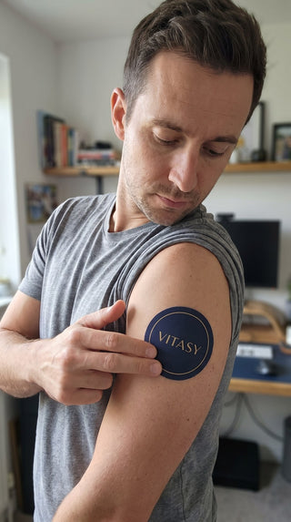 Man applying a Vitasy patch to his upper arm