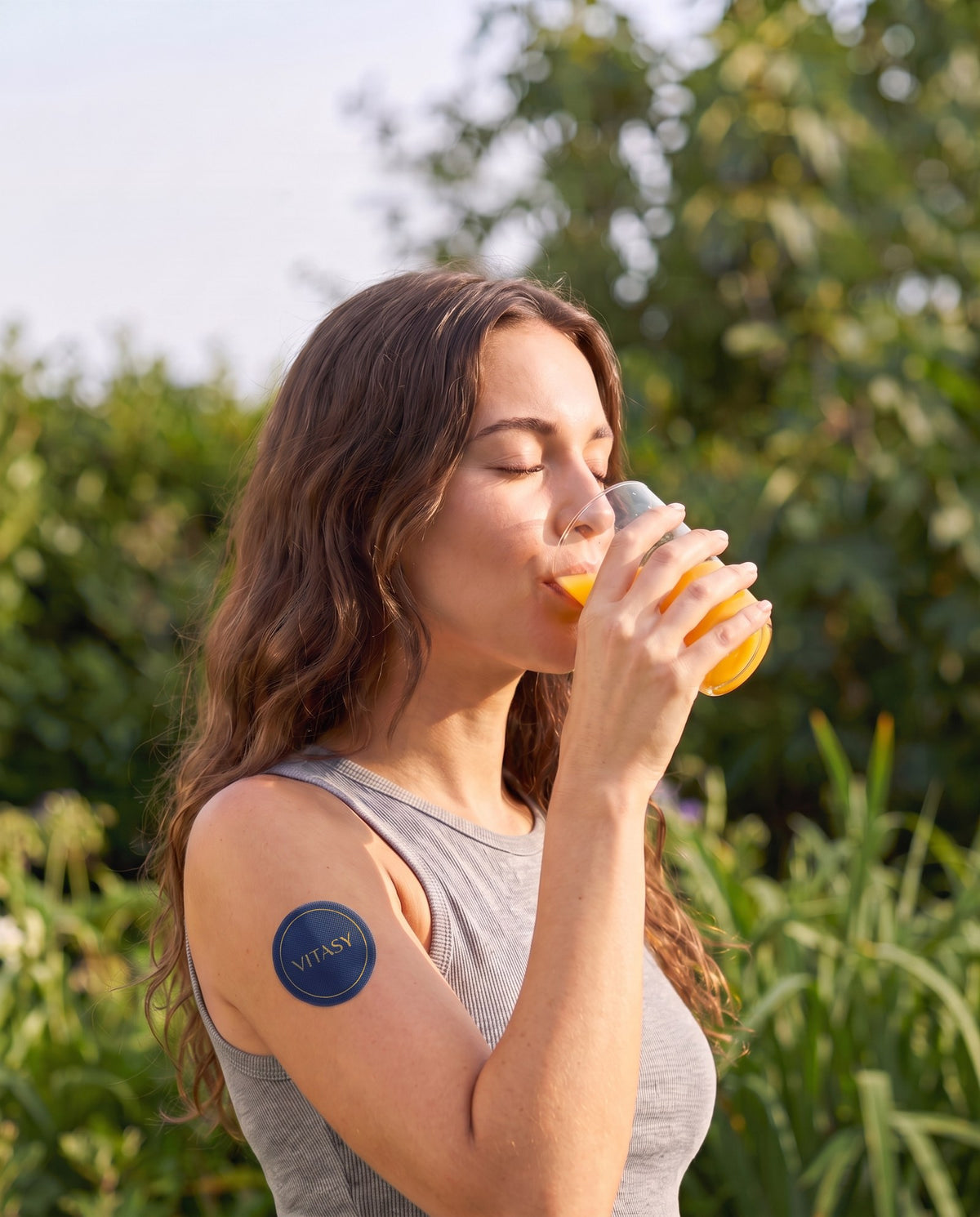 Woman with a Vitasy patch on her arm enjoying a drink outdoors
