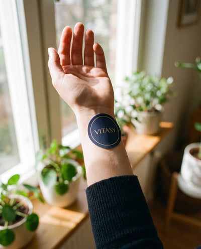 Round navy Vitasy patch on the inner wrist