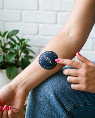 Round navy Vitasy patch on the forearm