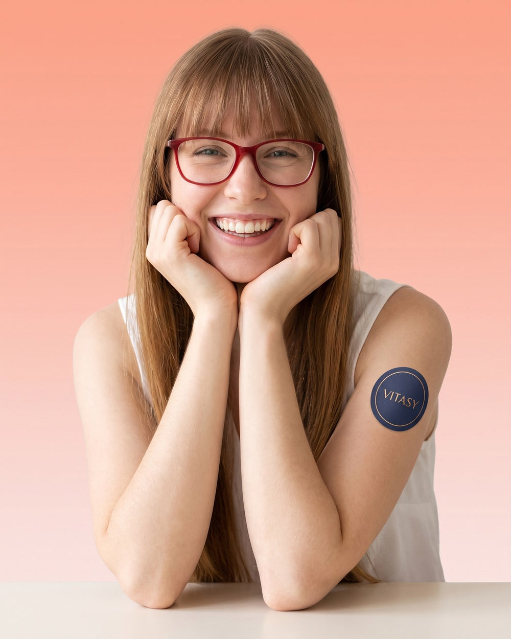 Smiling woman with glasses wearing a Vitasy patch on her upper arm