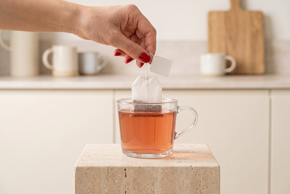 Tea bag being lowered into a glass of herbal tea
