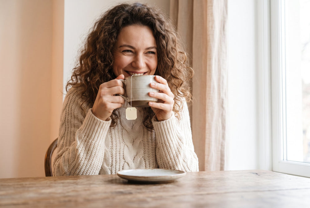 Woman smiling while drinking a cup of herbal tea
