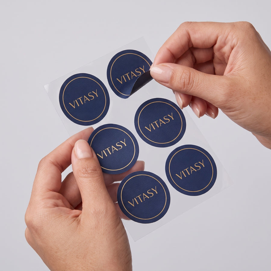 Hands peeling a Vitasy patch off a sheet of patches