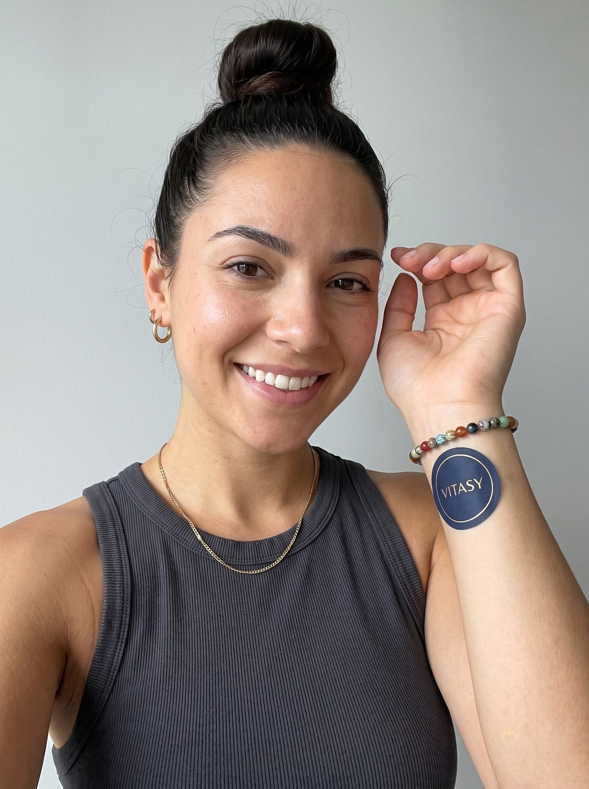 Smiling woman showing a Vitasy patch on her inner forearm