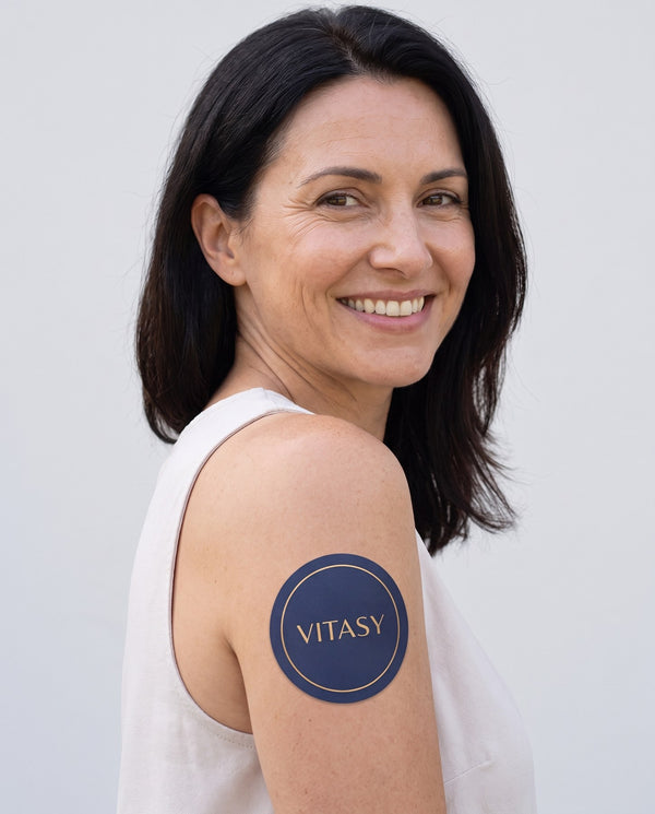 Smiling woman with a Vitasy patch on her upper arm