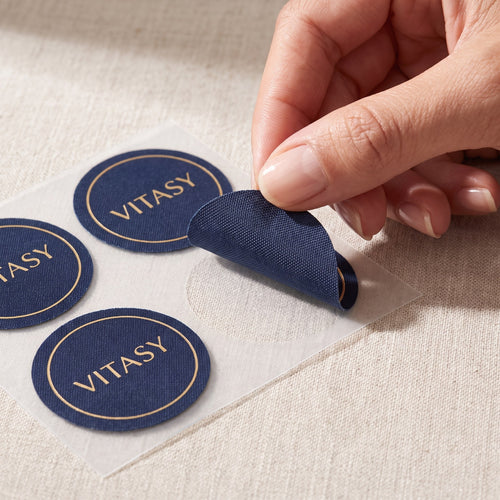 Fingers peeling a Vitasy patch from its backing sheet
