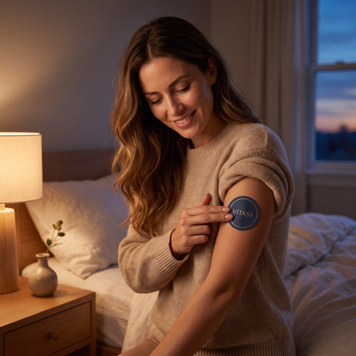 Woman pressing a Vitasy patch onto her upper arm in the evening