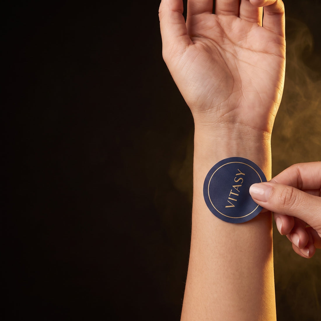 Hand applying a Vitasy patch to the inner wrist