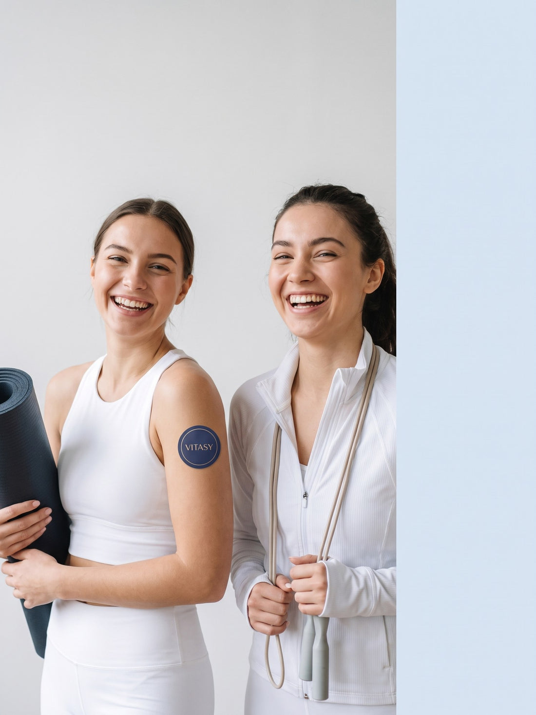 Two women in white activewear, one with a Vitasy patch on her upper arm