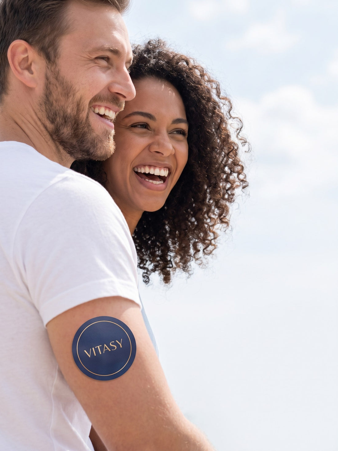 Laughing couple outdoors, the man wearing a Vitasy patch on his upper arm