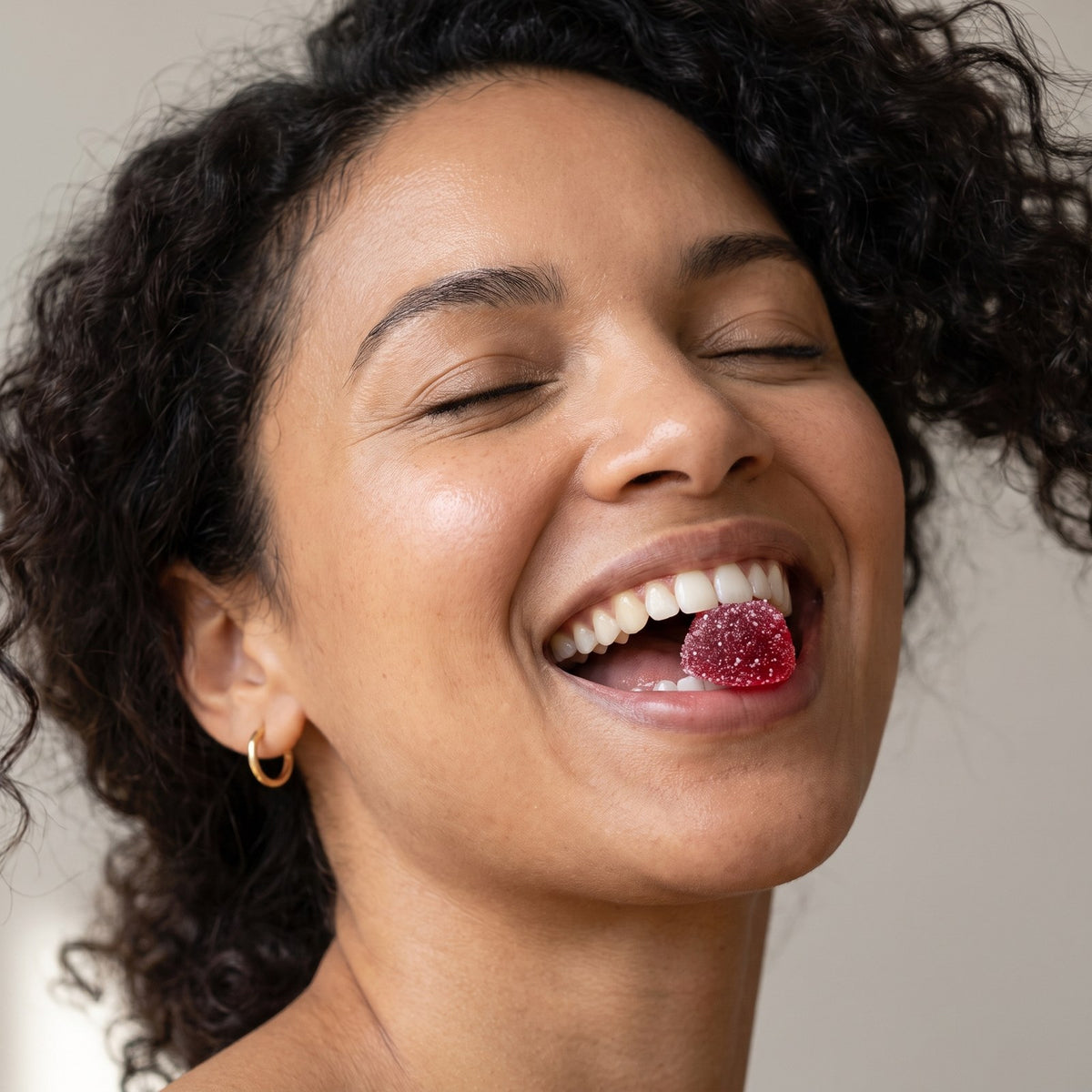 Smiling woman enjoying a red mixed berry saffron gummy