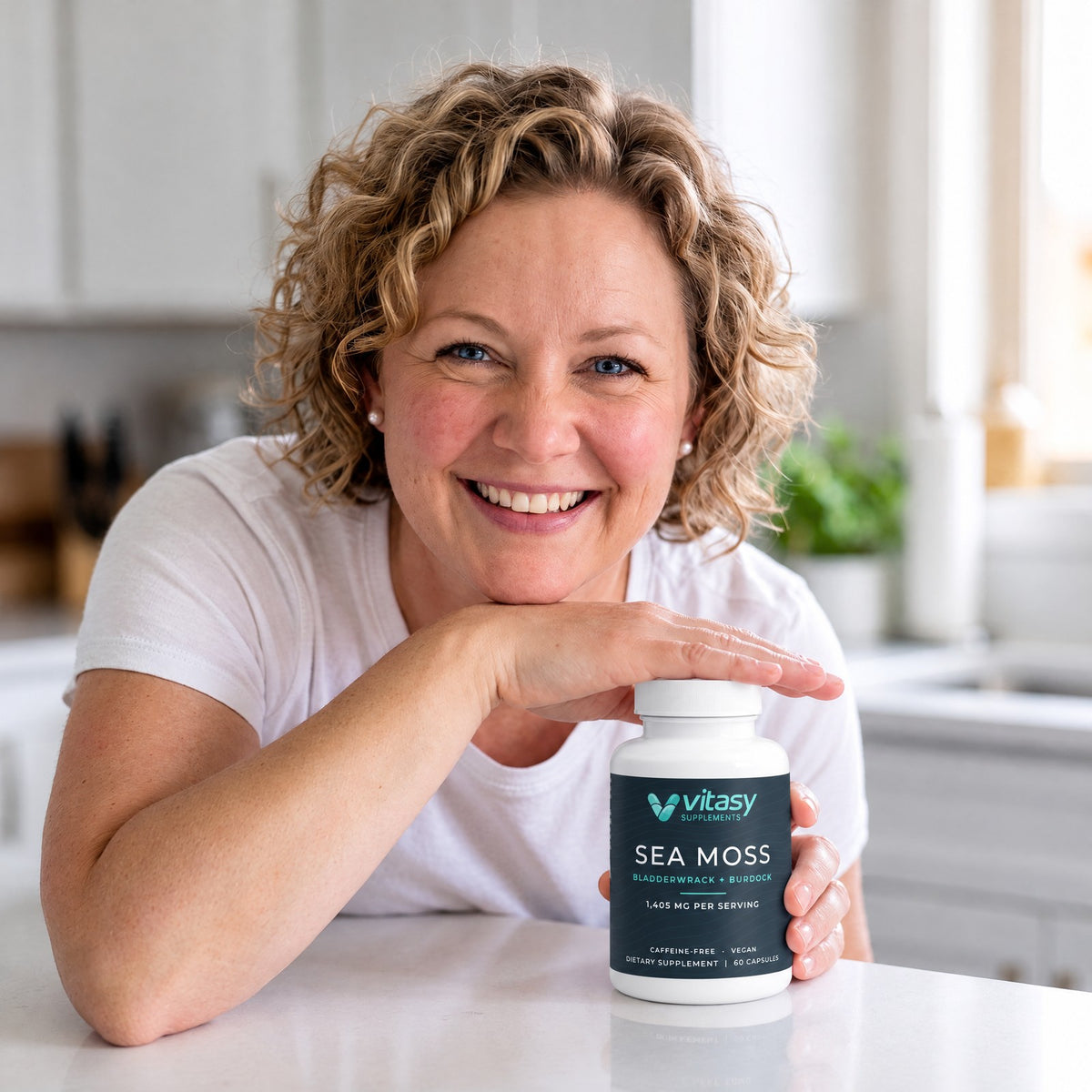 Woman leaning on a white kitchen counter next to a bottle of Vitasy Sea Moss Capsules