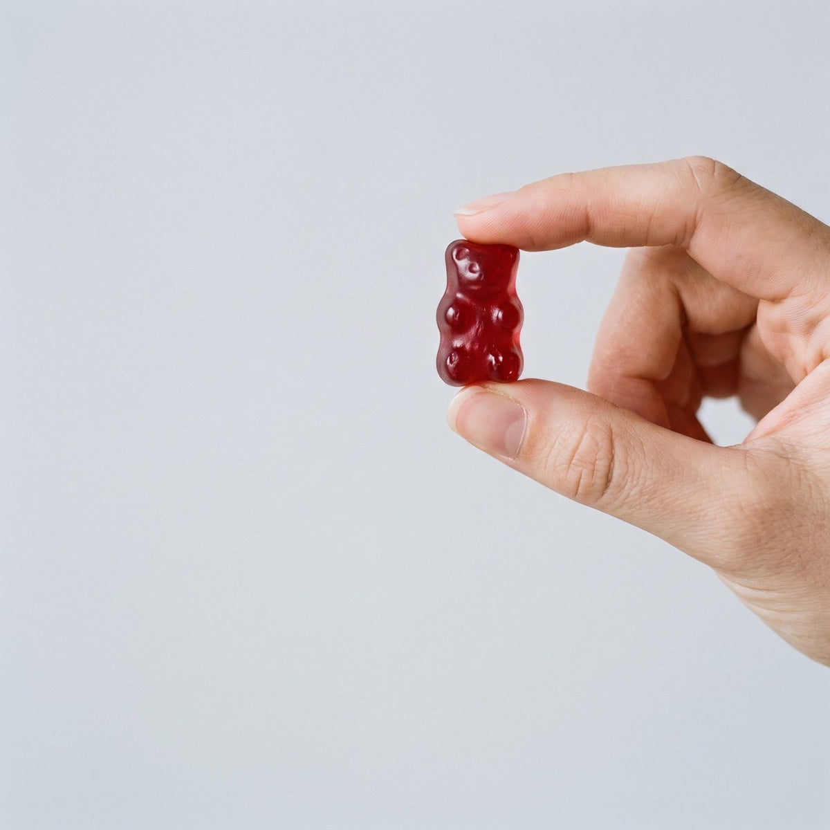 Hand holding one red apple cider vinegar gummy