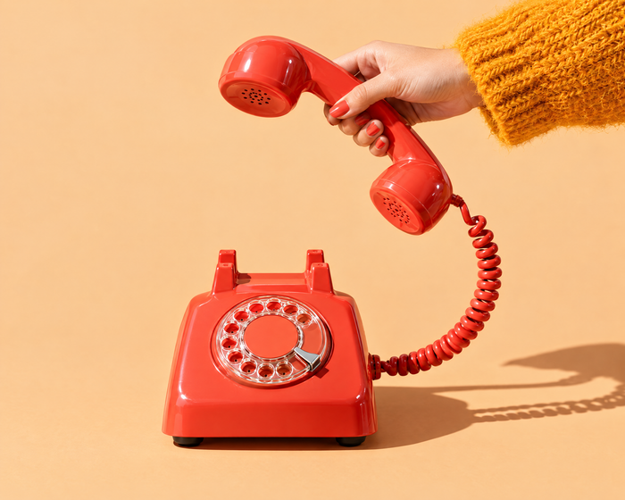 Hand lifting a red telephone receiver