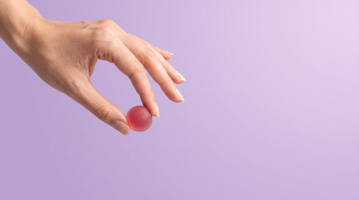 Hand holding one pink gummy
