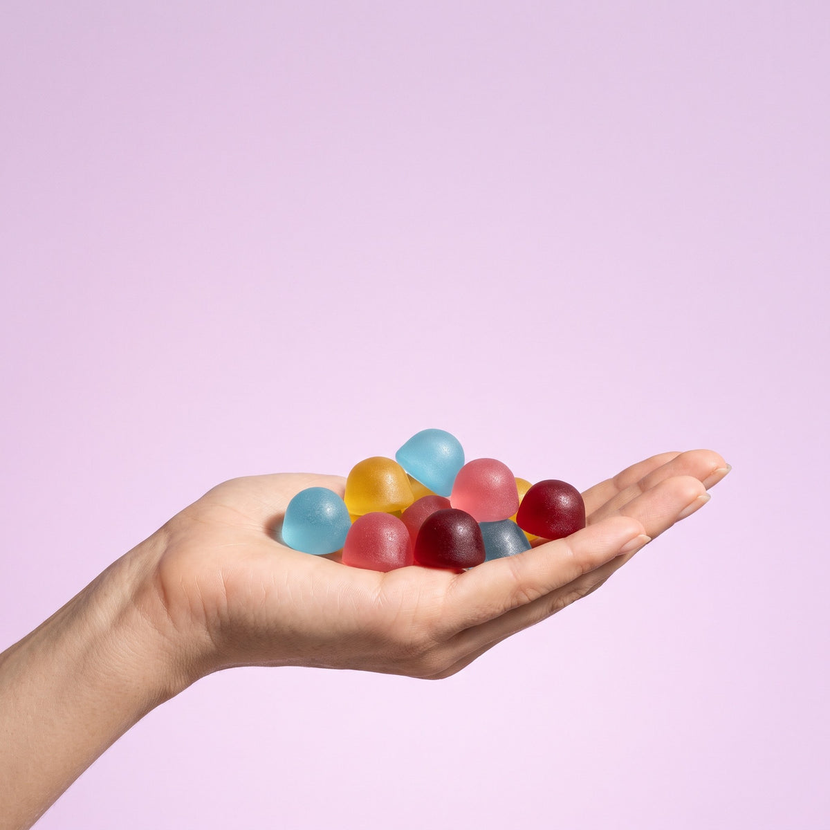 Hand holding a mix of fruity gummies
