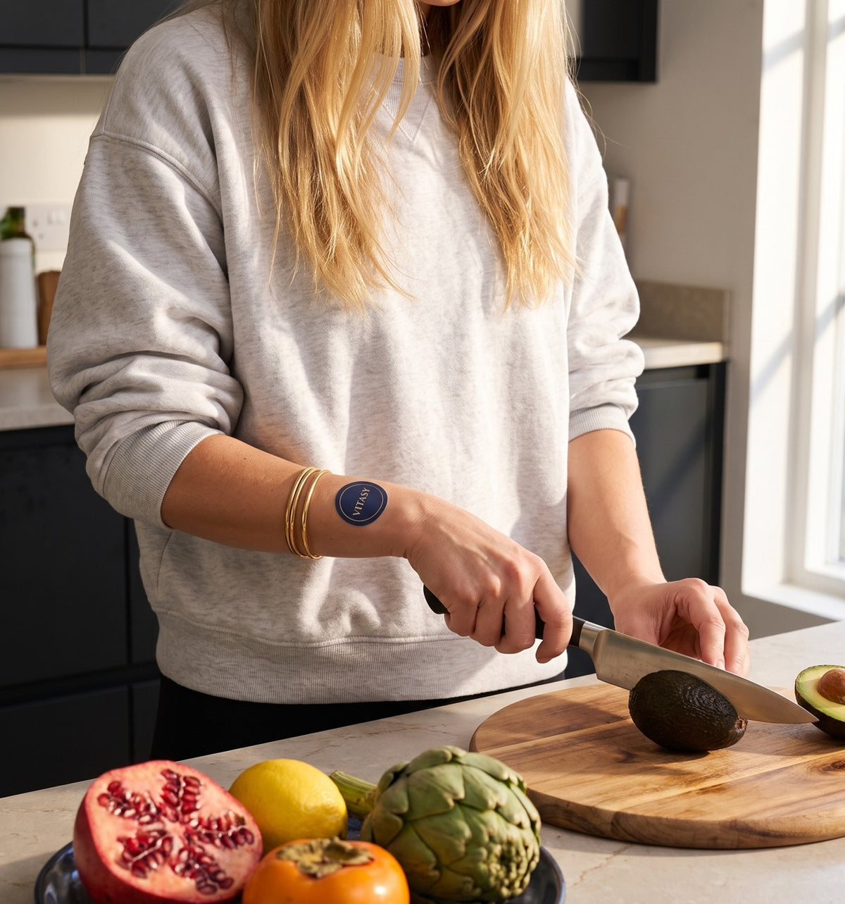 Woman preparing fresh fruit in the kitchen while wearing a Vitasy patch on her forearm