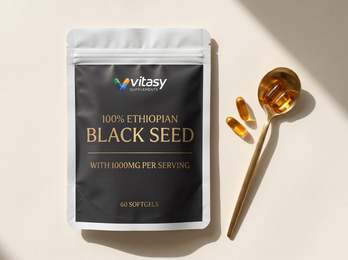 Vitasy Ethiopian Black Seed pouch lying next to a gold spoon with amber softgels
