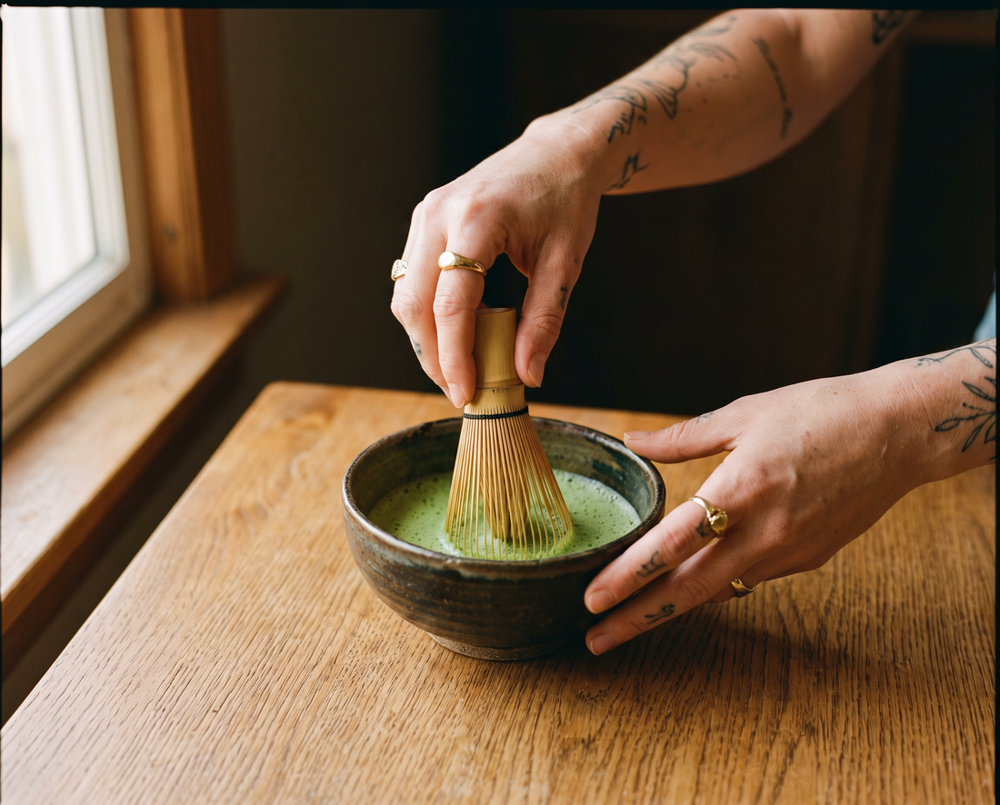 Hands whisking a matcha latte in a stoneware bowl