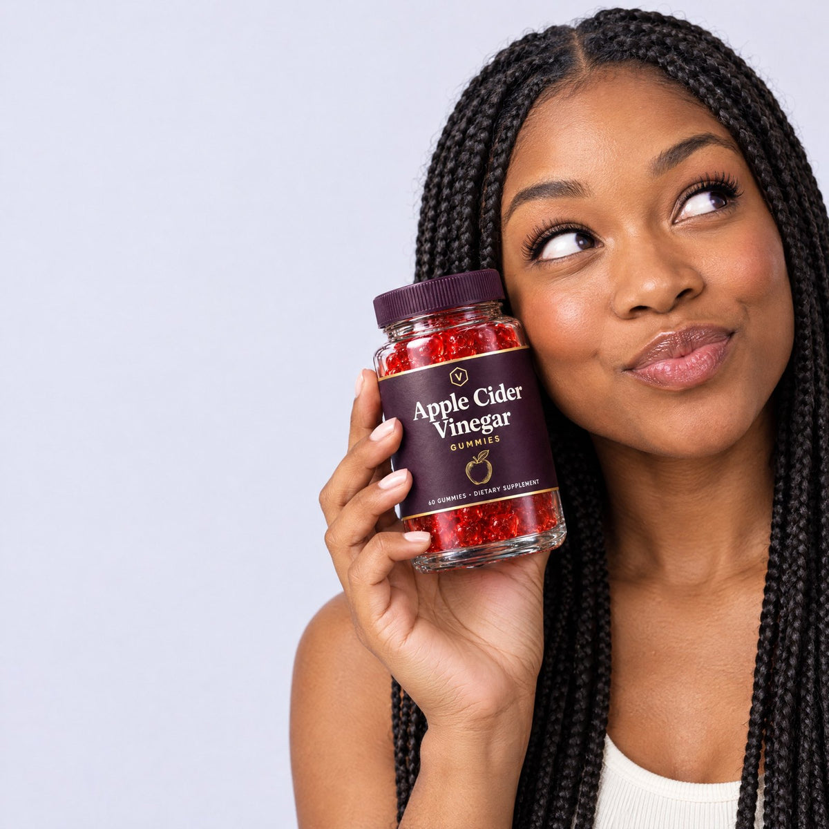 Woman holding a jar of Vitasy Apple Cider Vinegar Gummies next to her face