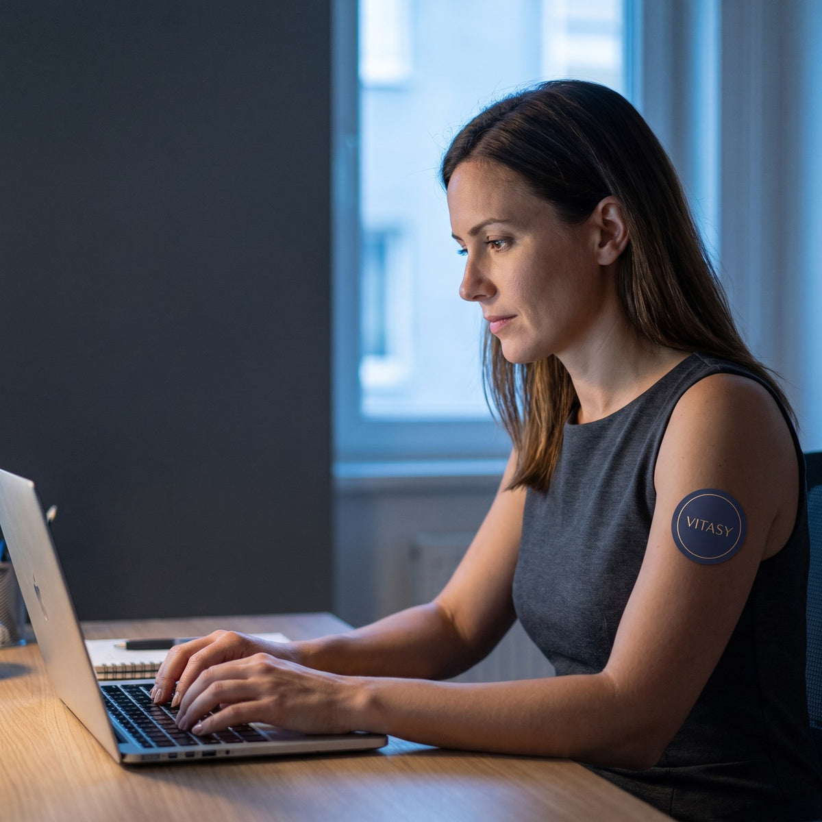 Woman working at a desk wearing a Vitasy Focus Patch
