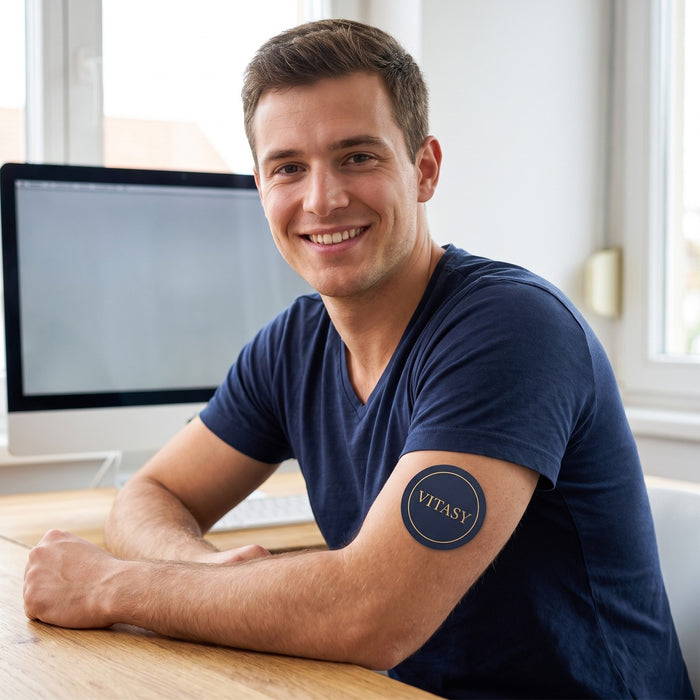 Smiling man at his desk with a Vitasy patch on his upper arm