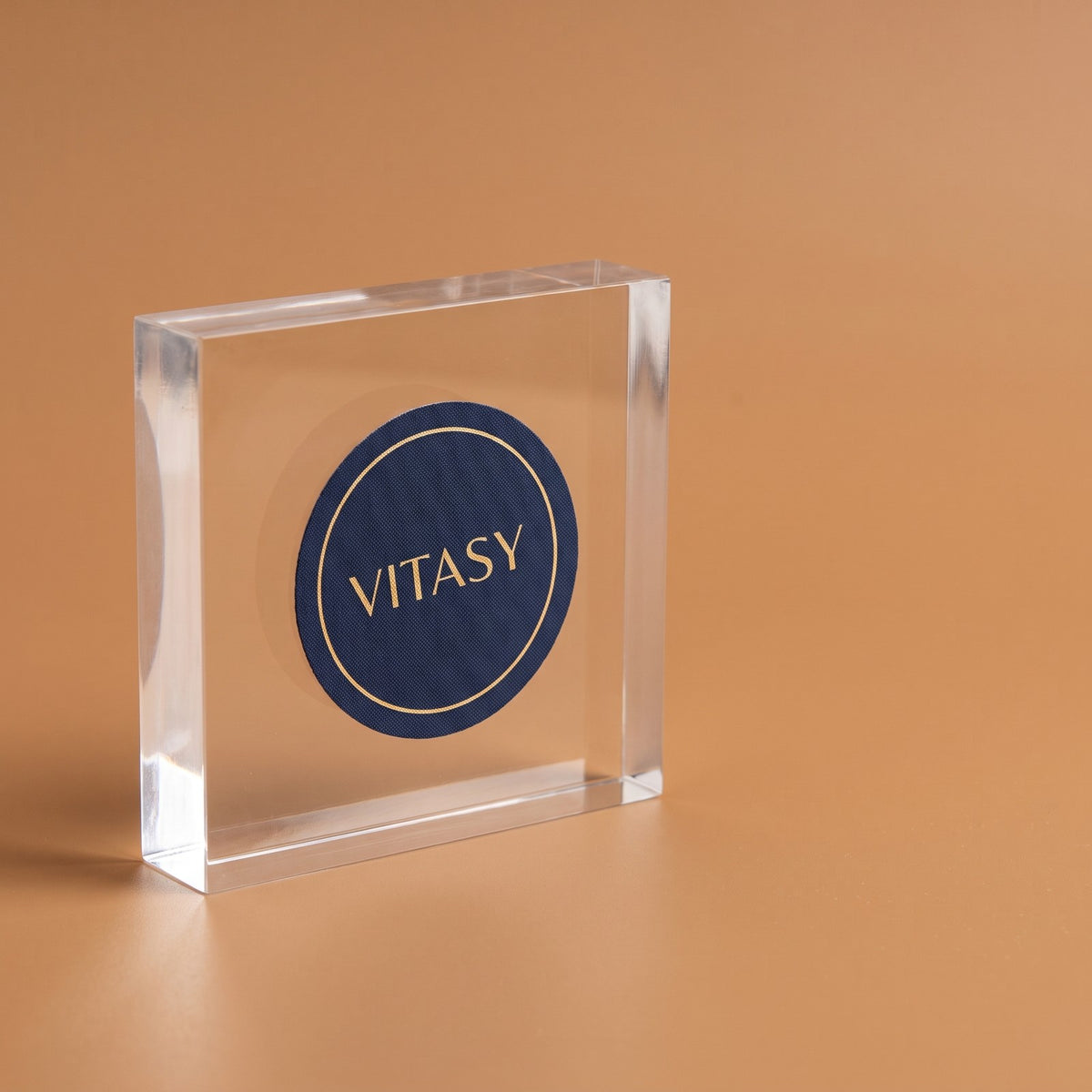 Close-up of a round navy Vitasy patch on a clear acrylic block