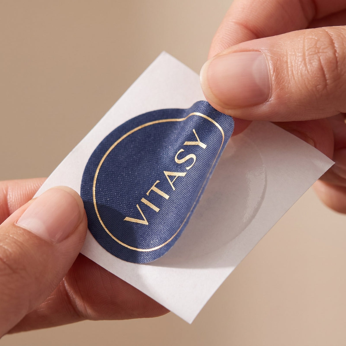 Fingers peeling a navy Vitasy patch from its liner