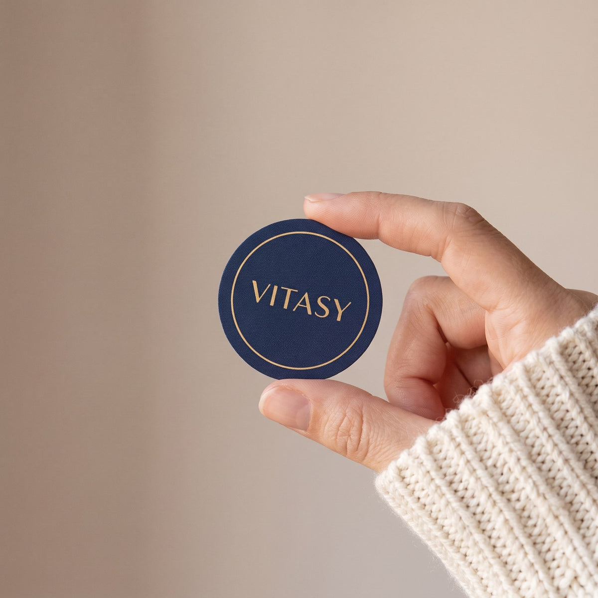 Hand holding a round navy Vitasy patch