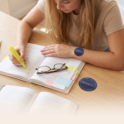 Woman studying at a desk wearing a Vitasy patch on her wrist