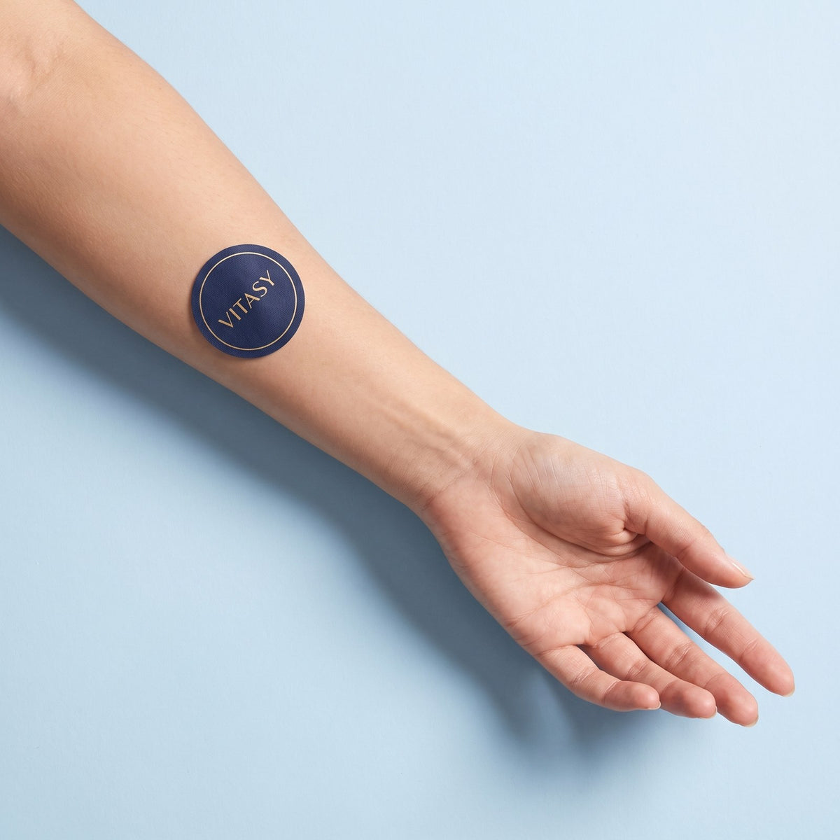Round navy Vitasy patch on a forearm