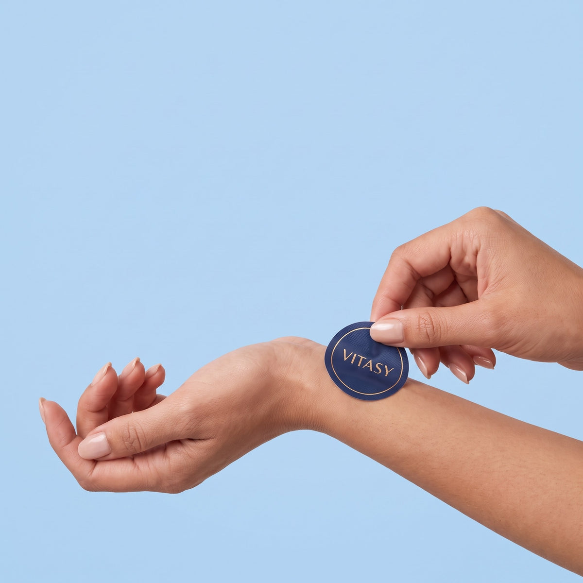 Peeling a round navy Vitasy patch from its sheet and applying it to the wrist