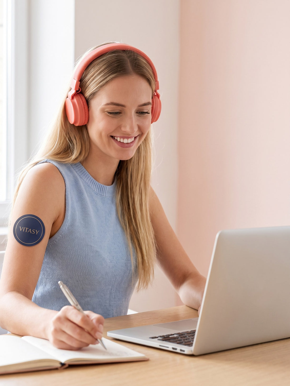 Woman with headphones working at her desk wearing a Vitasy patch