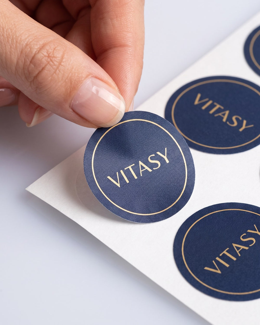 Fingers peeling a Vitasy patch from its backing sheet