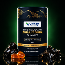 Shilajit Gold Gummies tube lit against a dark background with a green glow, raw shilajit resin and amber gummies at its base