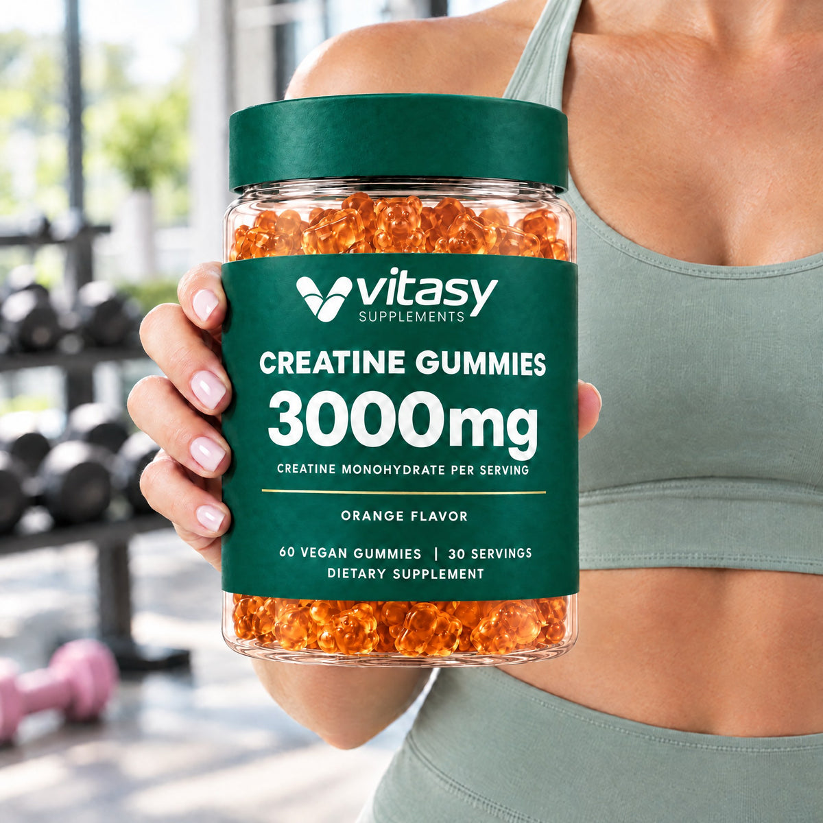 Woman in a gym holding a jar of orange Vitasy Creatine Gummies