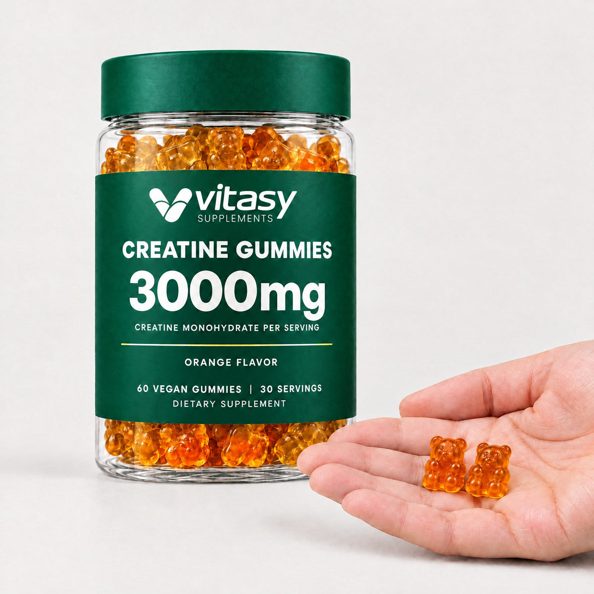 Two orange Vitasy creatine gummies in an open hand next to the jar