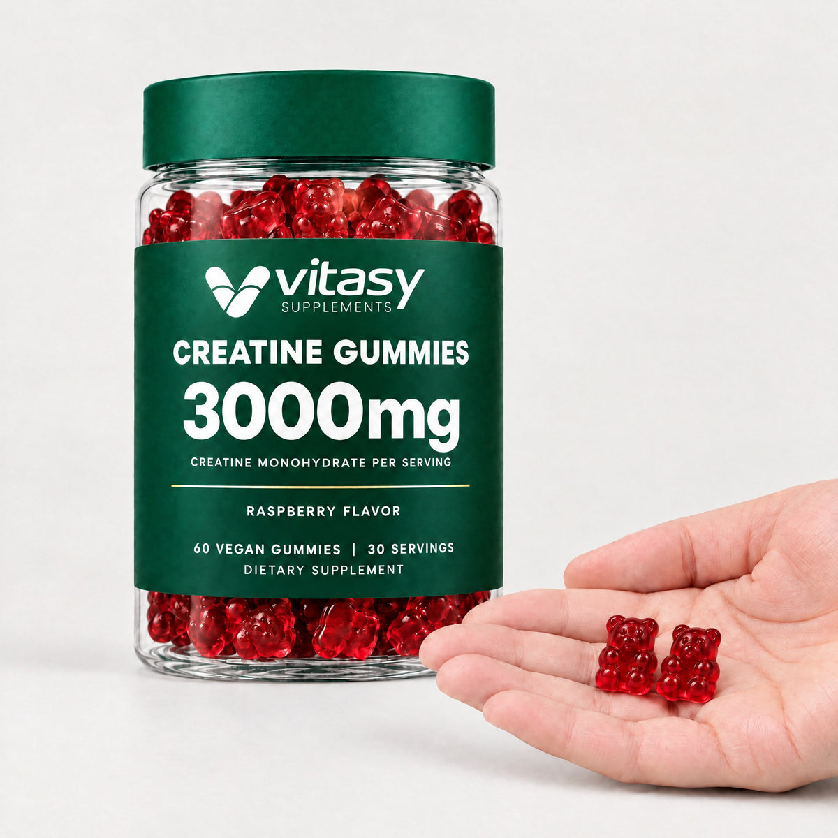 Two raspberry Vitasy creatine gummies in an open hand next to the jar