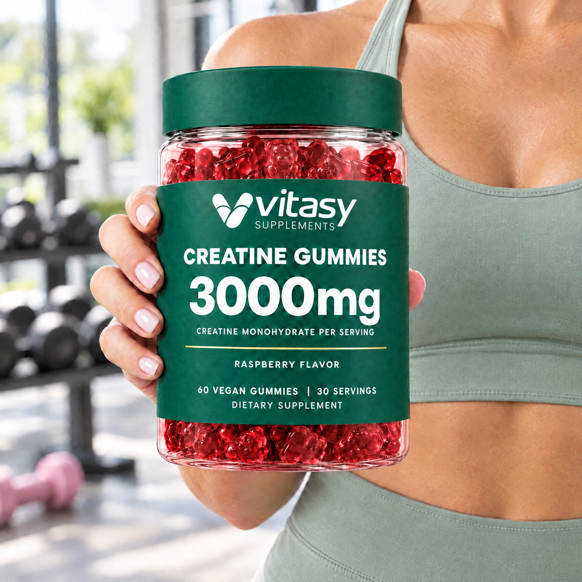 Woman in a gym holding a jar of raspberry Vitasy Creatine Gummies