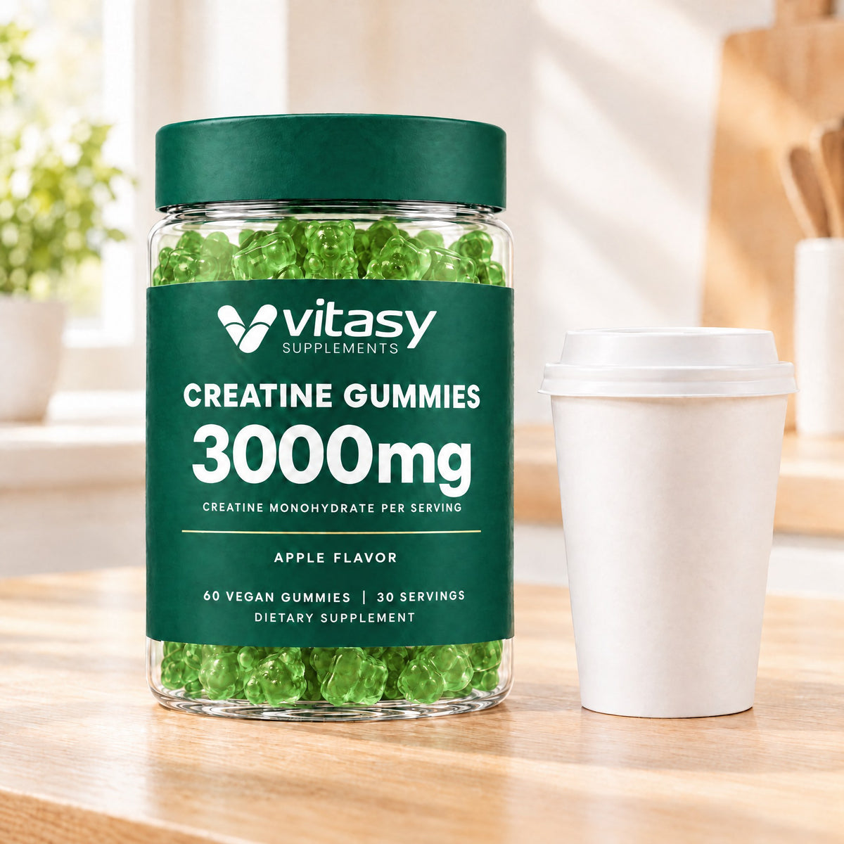 Apple Vitasy Creatine Gummies jar next to a coffee cup on a kitchen counter