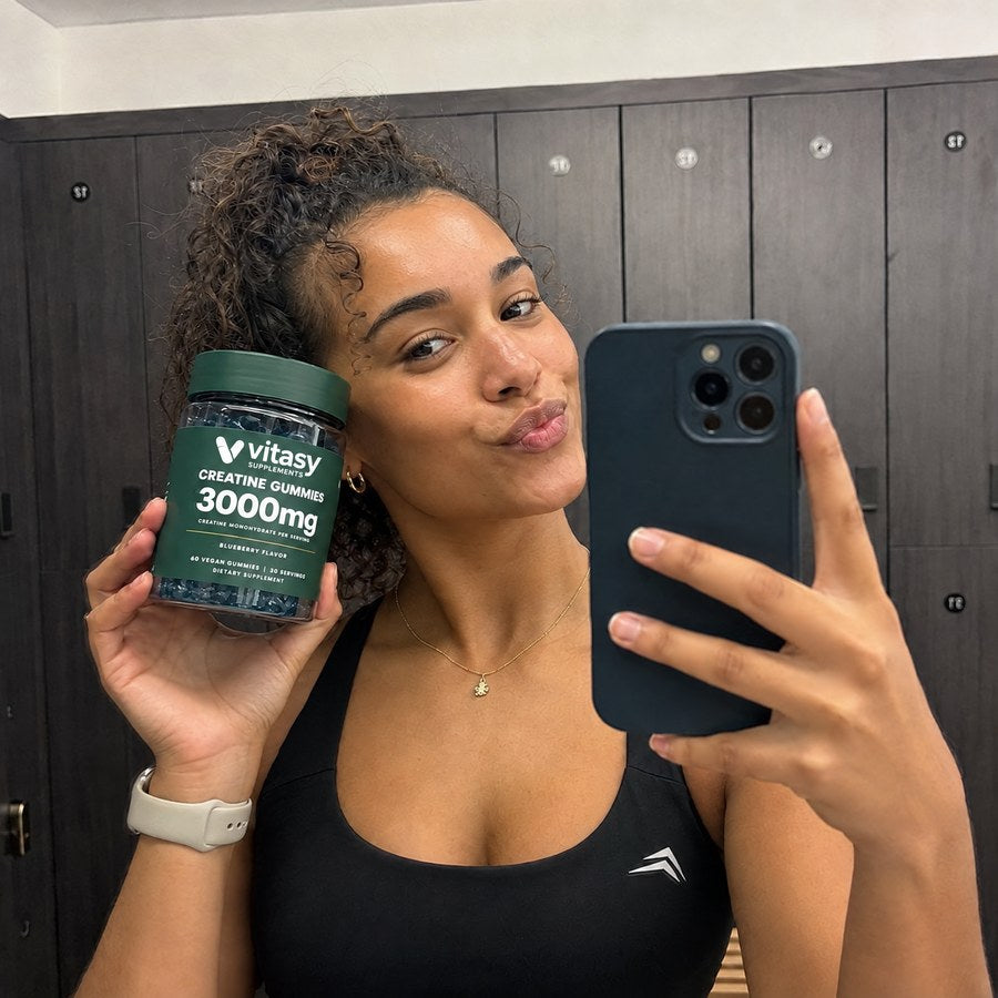 Woman in a gym locker room holding a jar of Vitasy Creatine Gummies