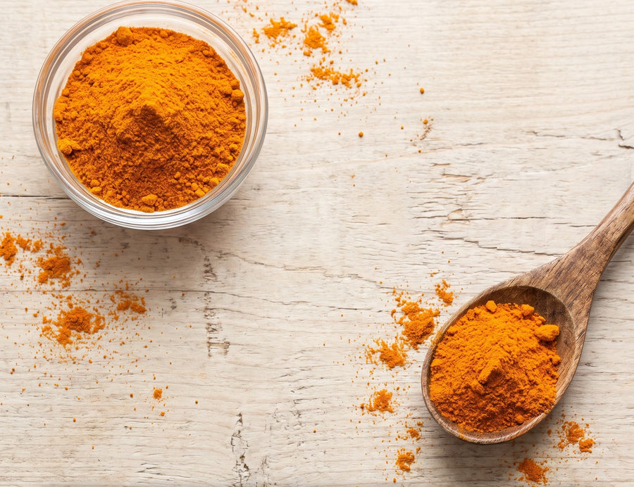 Orange CoQ10 powder in a glass bowl with a wooden spoon