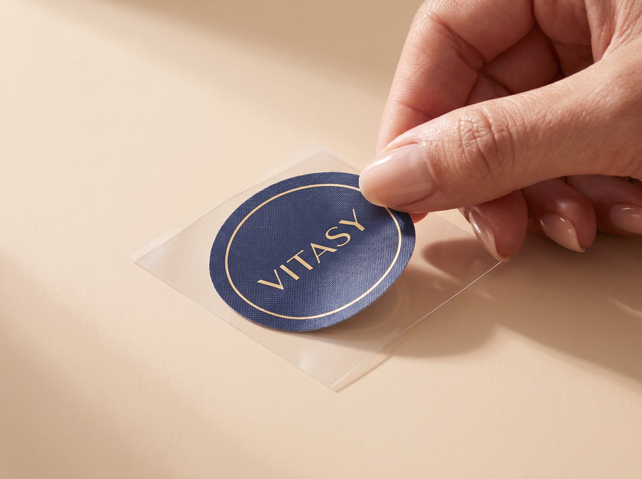 Fingers lifting a Vitasy patch off its clear backing liner