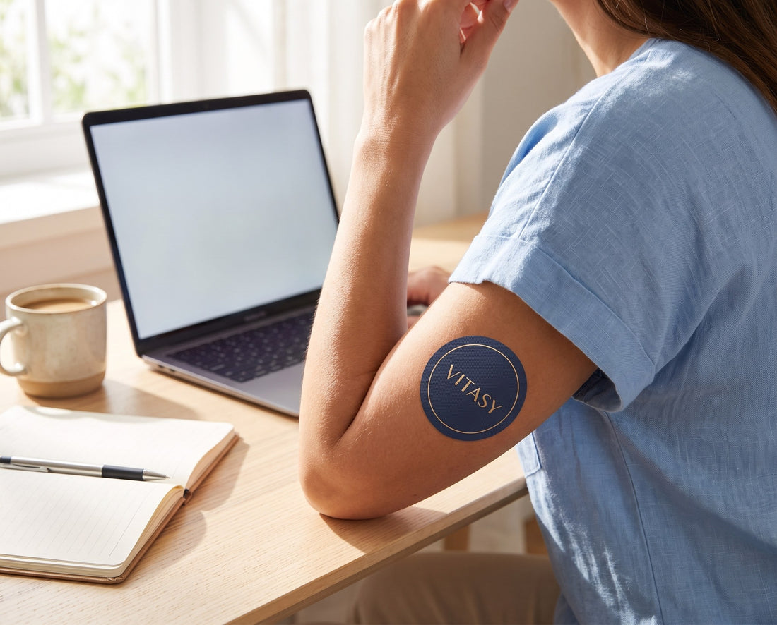 Arm with a Vitasy patch resting next to a laptop