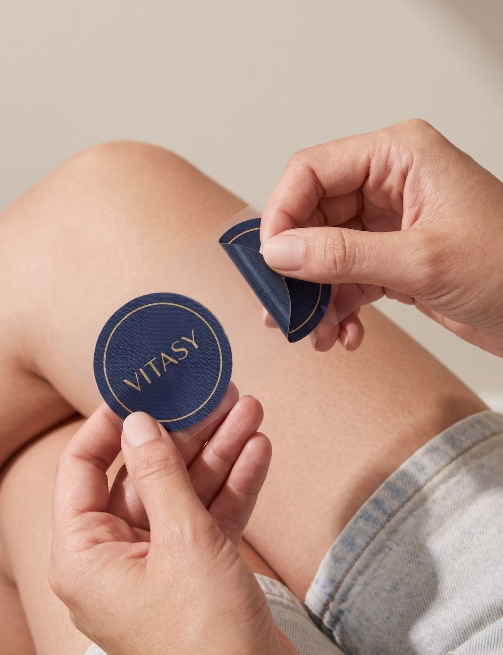 Hand peeling a Vitasy patch from its clear backing