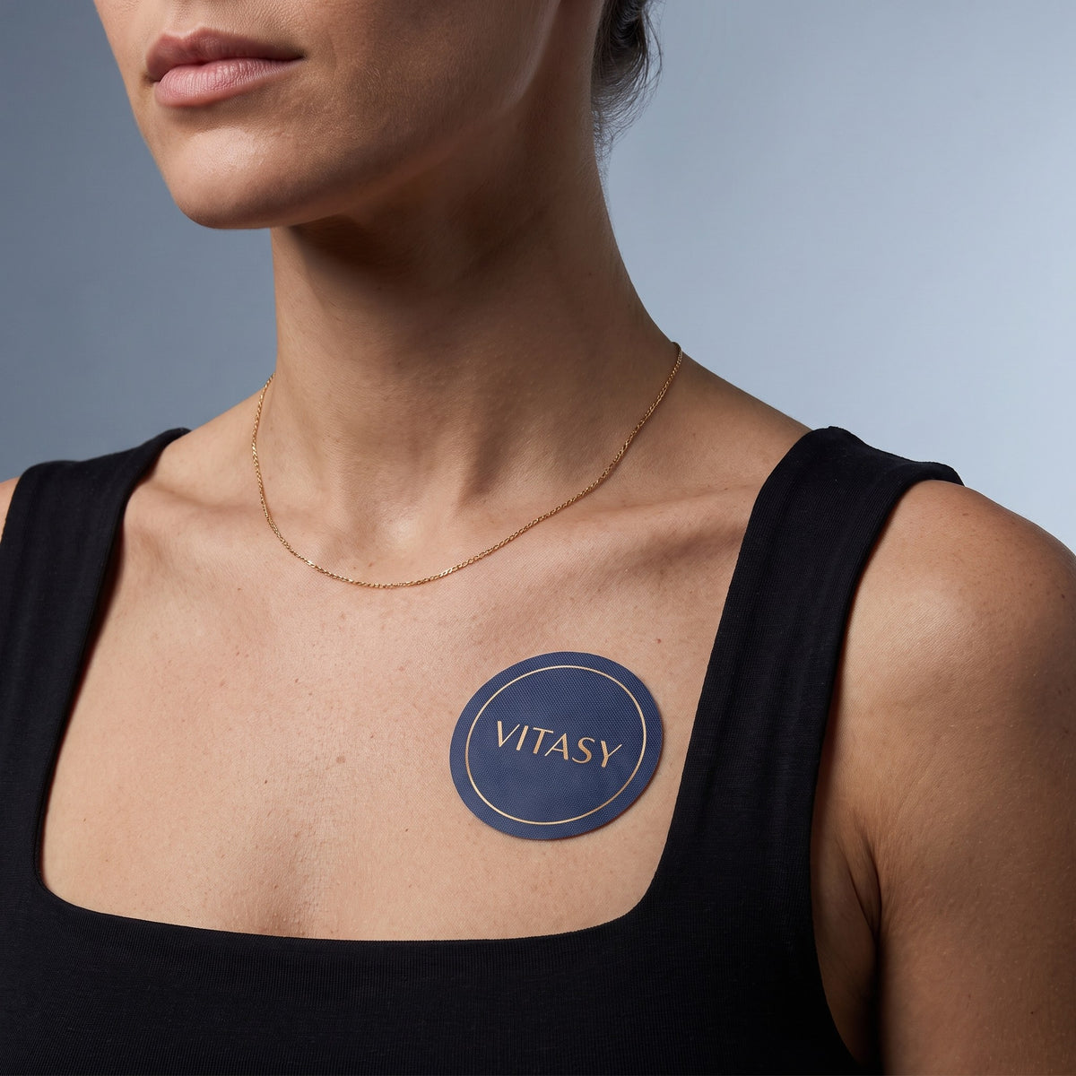 Woman wearing a Vitasy patch below the collarbone