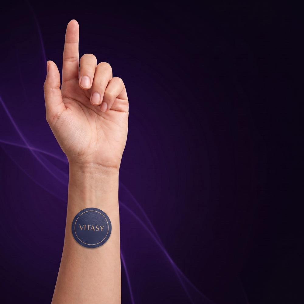 Raised hand with a Vitasy patch on the inner forearm