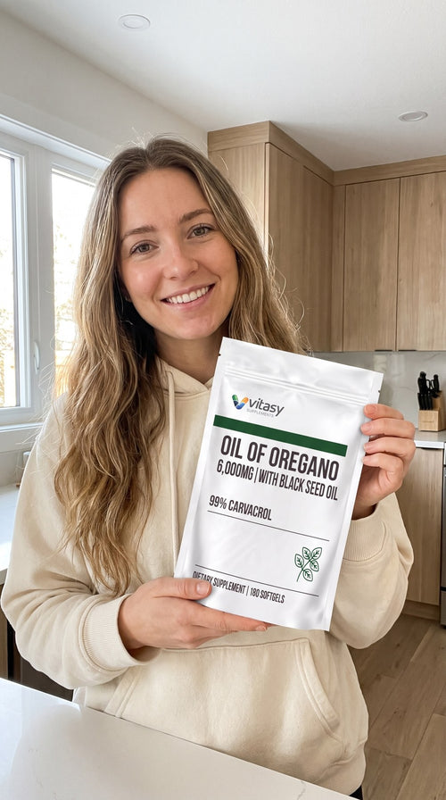 Young woman holding a pouch of Vitasy Oil of Oregano in her kitchen